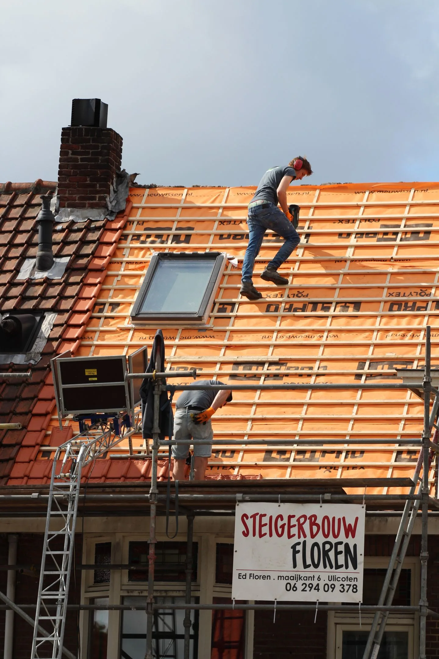 Dakwerkers plaatsen dakpannen op een gebouw in Nederland